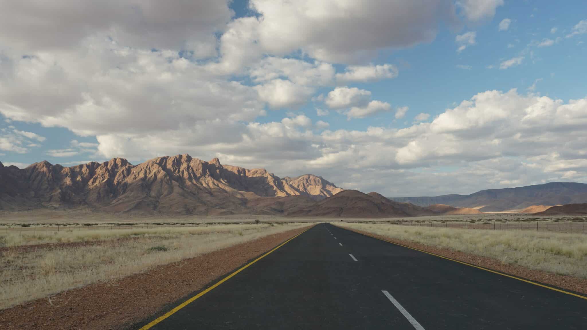 Asfalt weg in landschap Namibië met uitgestrekte steppe en bergen