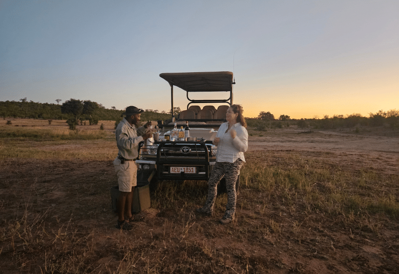 Een gids en een gast tijdens zonsondergang in de Afrikaanse wildernis van Hwange National Park in Zimbabwe